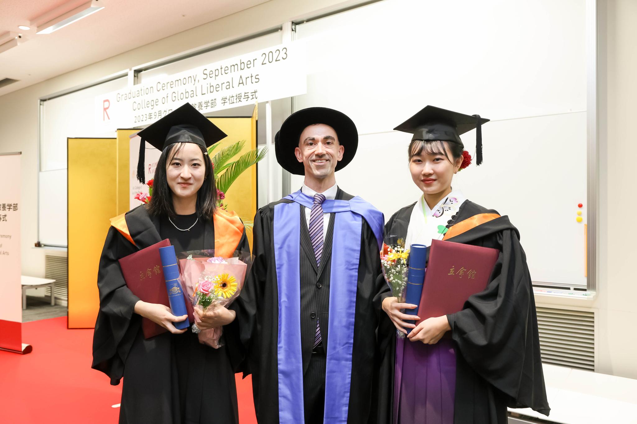 Three people standing in graduation robes and hats