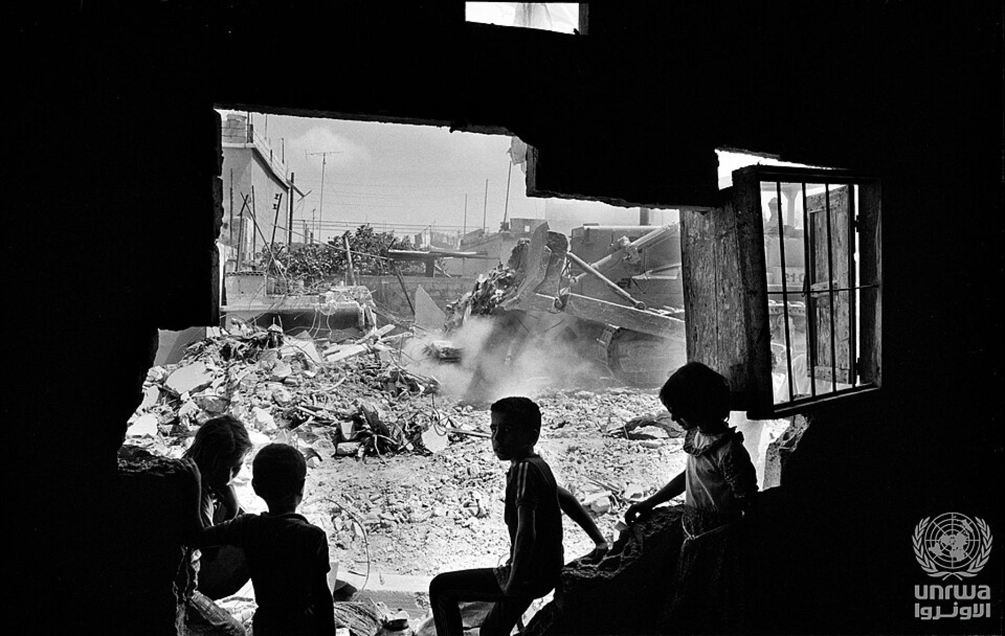 Children watching a bulldozer pushing remains of a destryed sheéter in Ein Hilweh camp, Lebannon