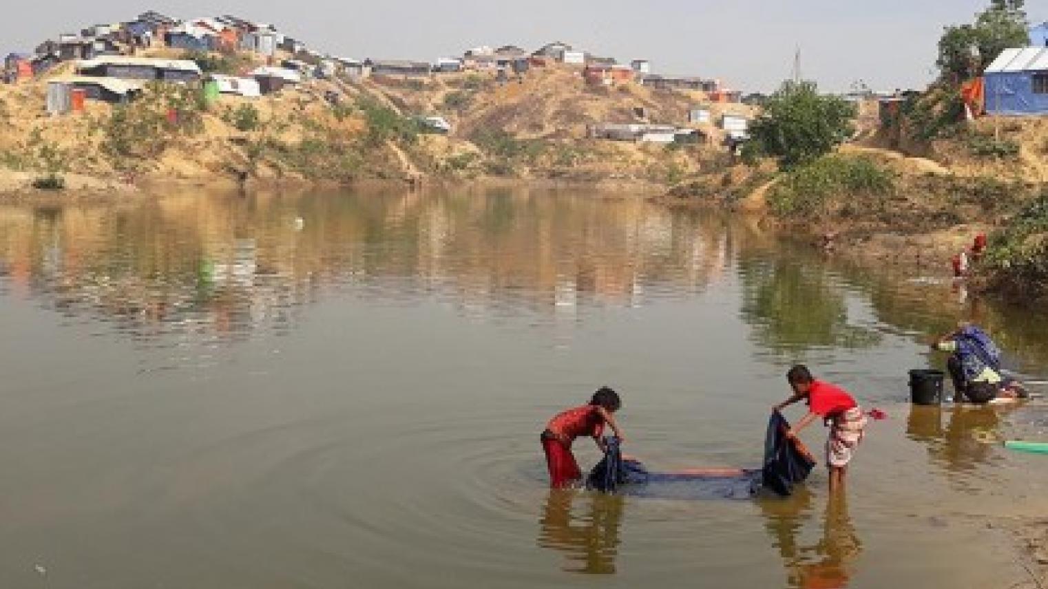 Refugee children washing in pond