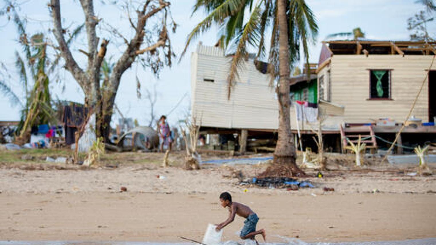 (c) UNICEF/UN0400159/Stephen/Infinity (Fiji 2020) Penioni Turaga, 7, races past the water’s edge, behind him a house destroyed by Tropical Cyclone Yasa, Galoa Village, Bua.